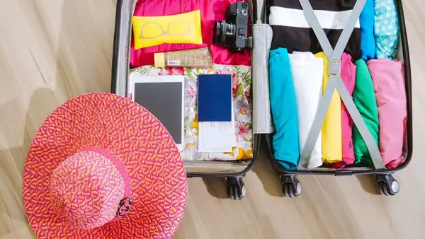 Spakovan kofer sa odećom, fotoaparatom i šeširom